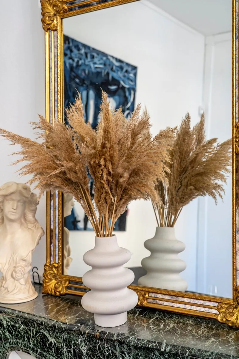 Miroir doré et vases de pampa sur une cheminée en marbre